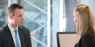 Dwóch elegancko ubranych osób omawiających dokumenty przy biurku jako symbol procesu reklamacji towaru i obowiązków sprzedawcy wobec kupującego